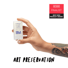 Load image into Gallery viewer, Hand holding the pocket-size balm stick, with the words Art Preservation and a NY NOW Best New Product Award finalist badge
